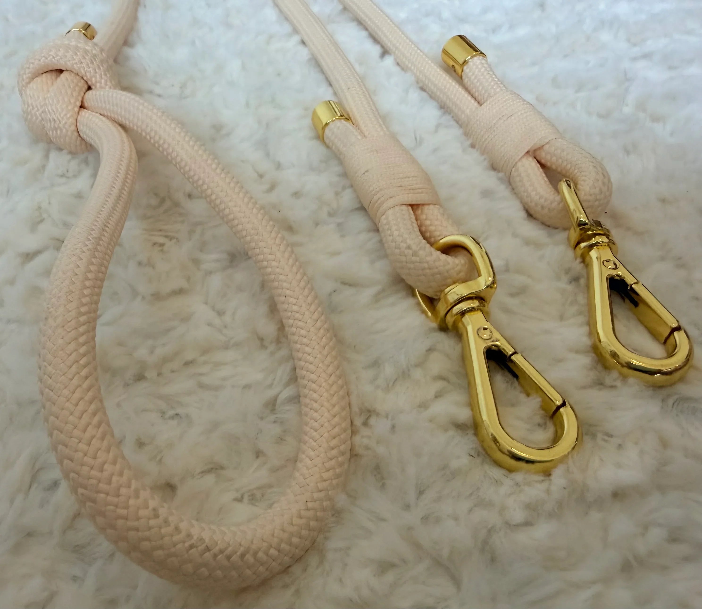 Beige rope dog leashes with gold clasps on a soft white surface, stylish pet accessory