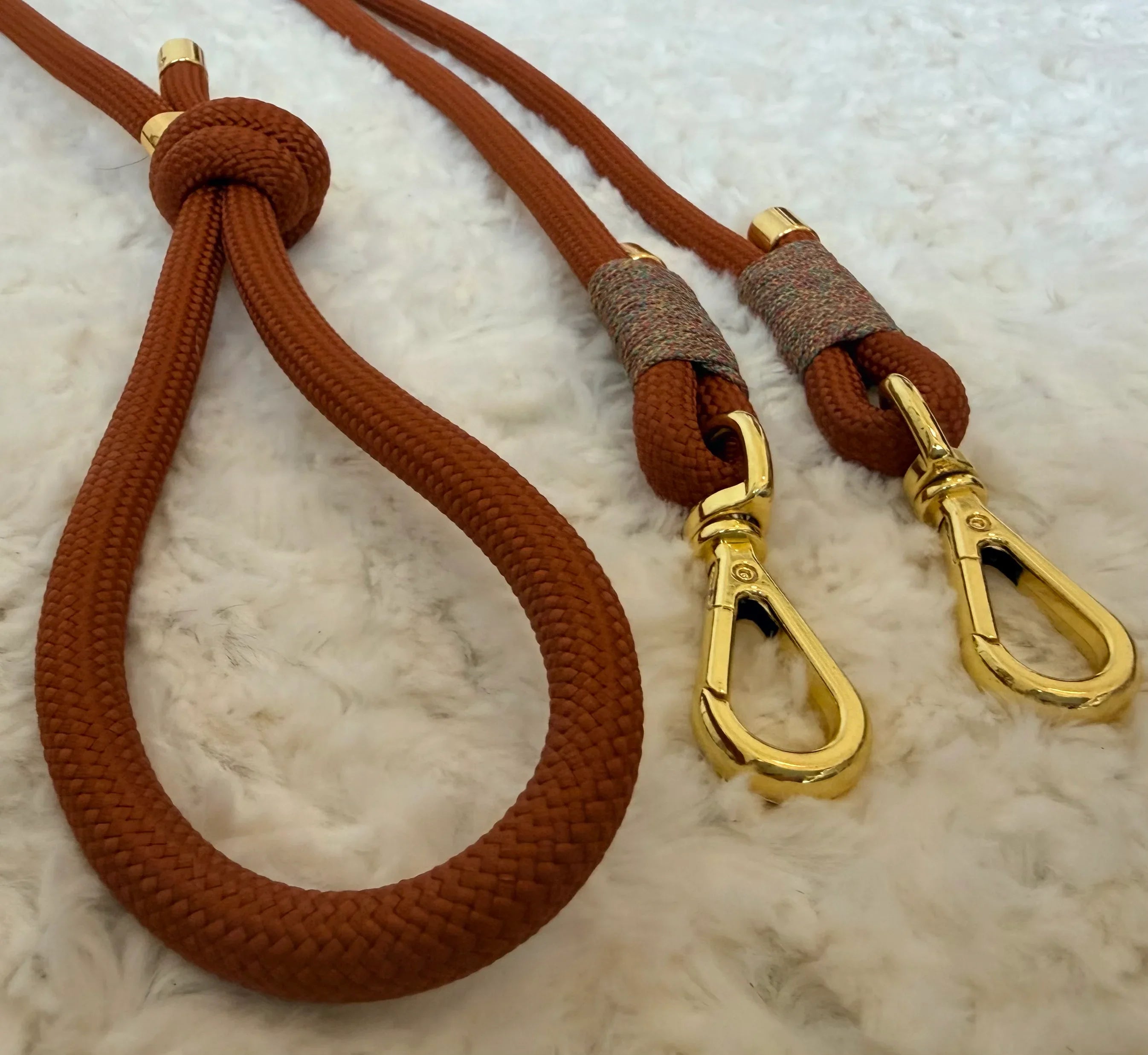 Brown rope dog leash with gold metal clips on white fluffy background, pet accessories