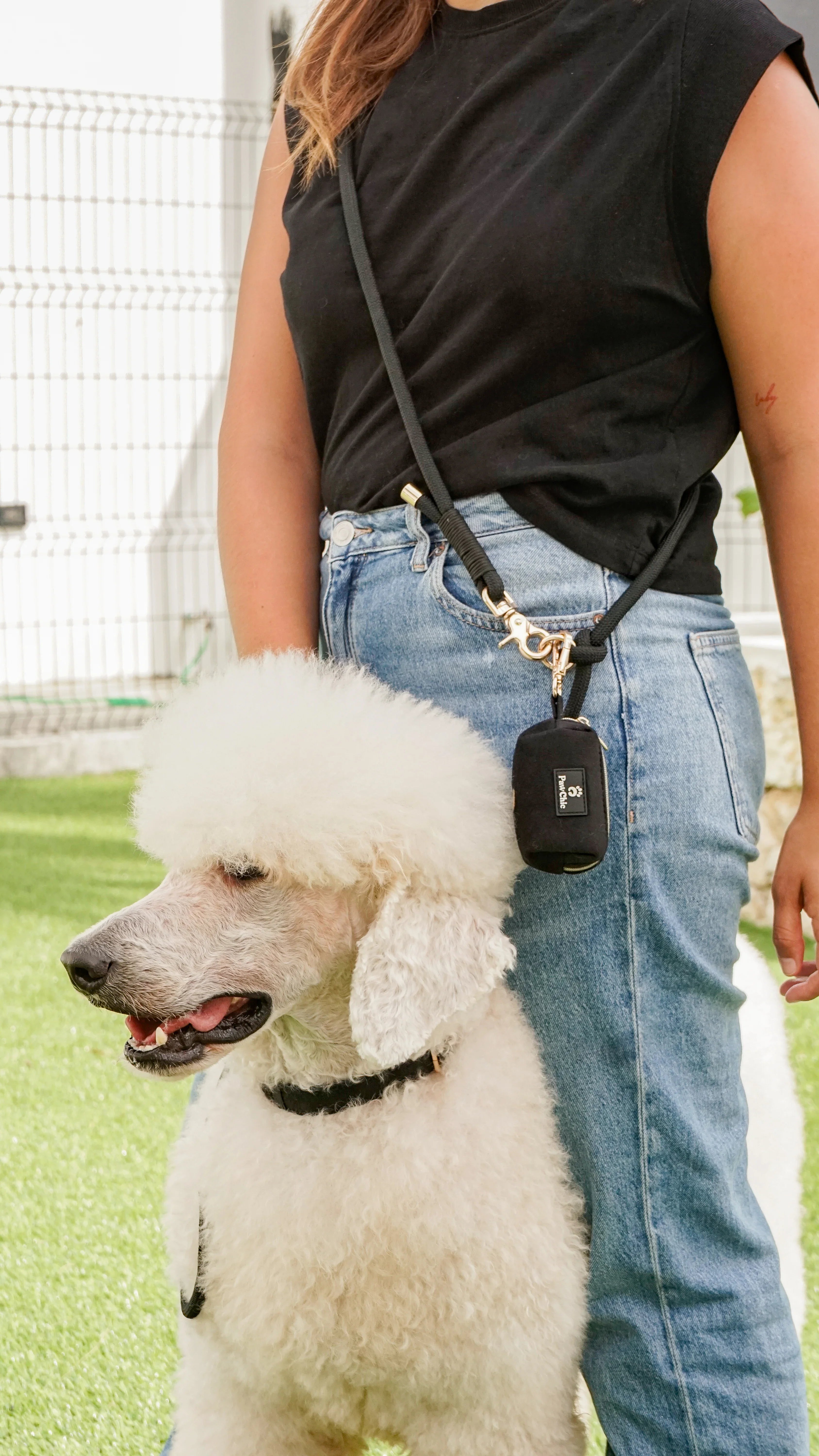 Woman with fluffy white poodle and black dog waste bag holder, pet accessories outdoors